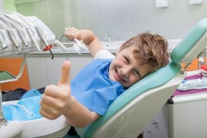 Kid sitting in chair with thumbs up