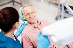 Senior man sitting in dentist chair smiling