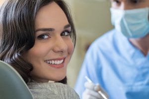 Woman smiling in dental chair before teeth cleaning