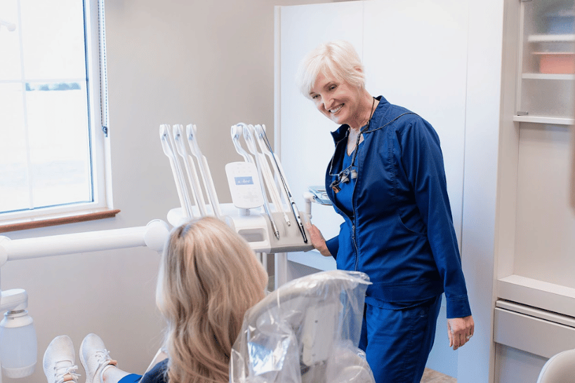 Female dentist explaining periodontal maintenance to patient in dental room